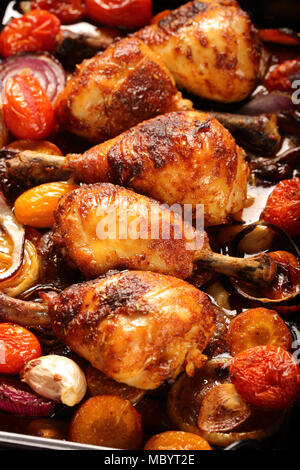 Arrosto di cosce di pollo con verdure su sfondo di legno Foto Stock