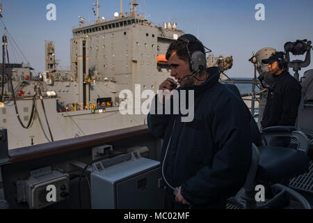 180105-N-DO281-1122 ARABIAN GLUF (GEN. 5, 2018) Intendente di terza classe Colton Benham sorge guarda come parlante telefono durante un rifornimento in mare, a bordo guidato-missili cruiser USS Monterey (CG 61). Il Monterey è distribuito negli Stati Uniti Quinta Flotta area di operazioni a sostegno della sicurezza marittima operazioni per rassicurare gli alleati e partner e preservare la libertà di navigazione e il libero flusso di commercio nella regione. (U.S. Foto di Marina di Massa Specialista comunicazione marinaio Trey Fowler) Foto Stock