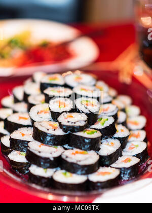 In prossimità di una piastra piena di rotoli di sushi. Foto Stock