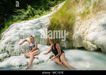 Due femmine in visita a fossa Bianca, White Whale, il carbonato di calcio delle sorgenti calde e piscine in travertino a Bagni San Filippo, sud della Toscana, Italia, Euro Foto Stock