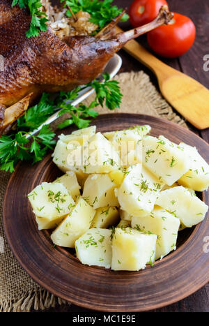 Patate bollite in un vaso di argilla close-up e oca arrosto Foto Stock