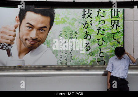 Salaryman giapponese in attesa di treni è preso nella stazione di Shinjuku, Giappone. Shinjuku è il più trafficato uno è il mondo. Foto Stock