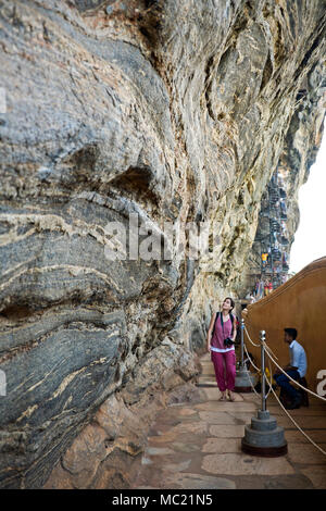 Vista verticale di un turista a piedi lungo la parete a specchio a Sigiriya o Lions Rock in Sri Lanka. Foto Stock