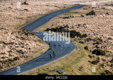 Due ciclisti percorrere una strada tortuosa attraverso Dartmoor nel Devon. Foto Stock