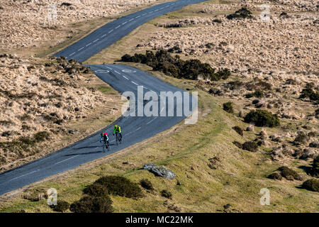 Due ciclisti percorrere una strada tortuosa attraverso Dartmoor nel Devon. Foto Stock