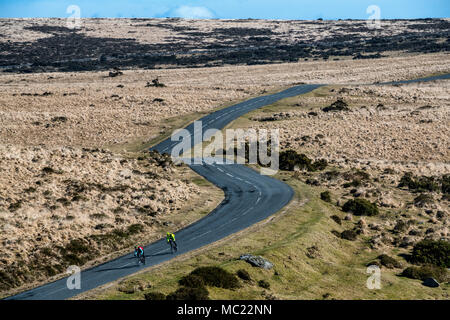 Due ciclisti percorrere una strada tortuosa attraverso Dartmoor nel Devon. Foto Stock