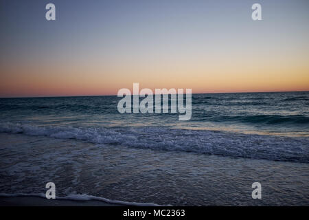 Bagliore dorato del tramonto su una calma Florida oceano su Anna Maria Island come il Gentle Waves lap la spiaggia Foto Stock