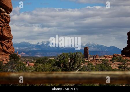 Una vista del Parco Nazionale di Canyonlands e montagne innevate con cielo nuvoloso, alcune formazioni rocciose in primo piano. Foto Stock