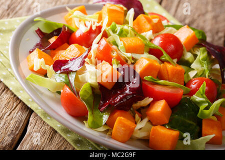 Insalata multicolore al forno con patate dolci, le verdure e le erbe conditi con olio di oliva close-up su una piastra su un piano orizzontale. Foto Stock