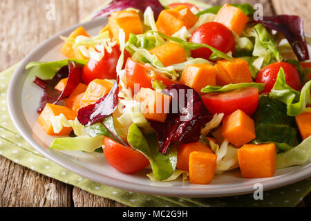 Vegetariano fresca insalata cotta al forno con patate dolci, le verdure e le erbe close-up su una piastra su un piano orizzontale. Foto Stock