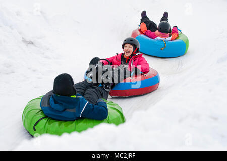 I bambini sulla neve tubi in discesa alla giornata invernale Foto Stock