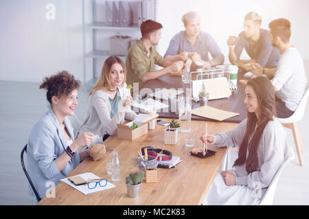 Persone sedute e parlando durante una pausa pranzo in ufficio Foto Stock