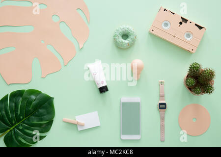 Cassetta di rosa, smartphone e guardare su Sfondo menta con foglia verde Foto Stock