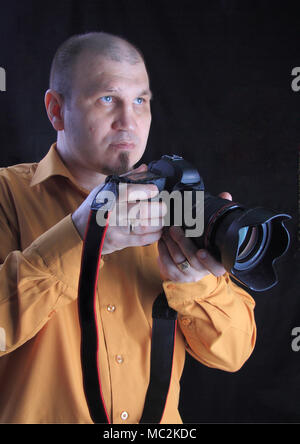 Fotografo professionista in Studio su uno sfondo nero con una macchina fotografica in mano. Foto Stock