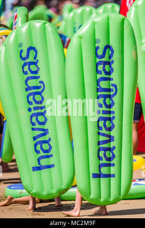 Beachgoers portante Havianas gonfiabile flip-flop in surf in Australia annuale evento della durata di un giorno, accogliente angolo, Torquay, surf Coast, Victoria, Australia Foto Stock