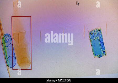 X-ray screenshot di un sacchetto con, da sinistra a destra : un flacone spray, una bottiglia di acqua e uno smartphone. Foto Stock