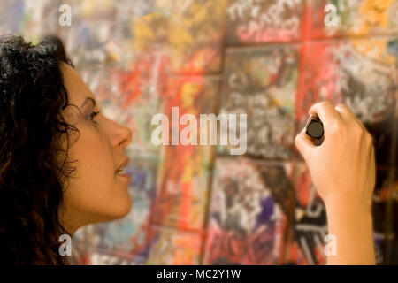 Donna pittura qualcosa su un muro di mattoni Foto Stock