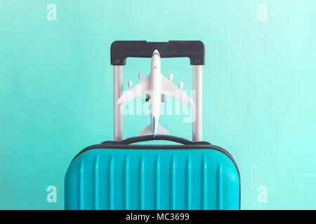 La valigia e il modello di aereo in verde pastello background creativo minimo concetto di viaggio Foto Stock