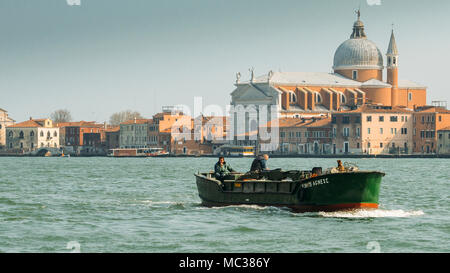 Barca commerciale con la Chiesa di San Giorgio Maggiore in background Foto Stock