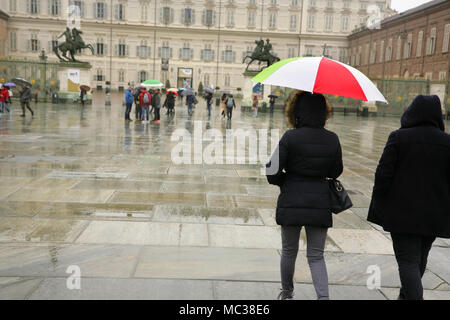 I turisti con ombrello con la nazionale italiana di colori in Piazza Castello, Torino, Italia, con il palazzo reale dietro. Foto Stock