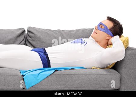 Uomo in un costume da supereroe di dormire su un divano isolati su sfondo bianco Foto Stock