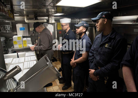 SASEBO, Giappone (27 marzo 2018) velisti assegnati per il Vendicatore di classe contromisure mine nave USS Chief (MCM 14) presente la nave di cucina per ispezione ad una scheda di ispezione e di indagine (INSURV) assessore. Chief sta subendo INSURV per esaminare la nave di capacità operativa e di disponibilità per il futuro la mia operazioni di spazzatura. Foto Stock