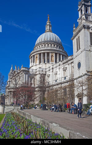 Città di Londra. Le persone che si godono il sole di aprile nella Cattedrale di St Paul giardini. La torre di Sant'Agostino Watling Street si trova sulla destra Foto Stock