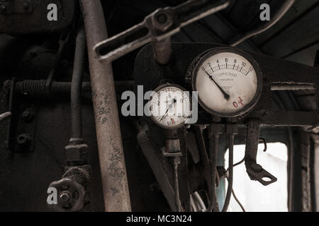 Dettagli degli interni della abbandonato il vecchio arrugginito locomotiva sovietica a piattaforma. Frenatura di due manometri vintage e tubi arrugginito. Scritto in russo su bianco Foto Stock