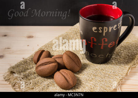 Un caffè in una tazza nera con i chicchi di caffè forma di cookie Foto Stock