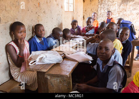 Uganda. Il 13 giugno 2017. Sorridente bambini ugandesi seduto alla scrivania in una classe in una scuola primaria. Foto Stock