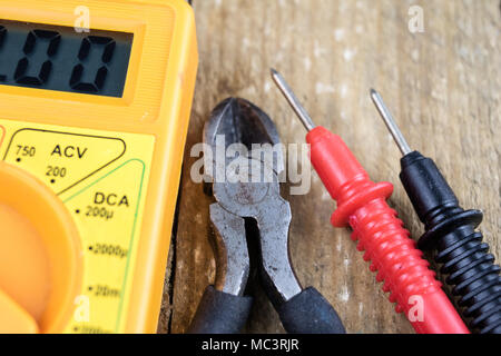 Accessori nel laboratorio di elettronica. Misuratore elettronico, saldatore e altri strumenti necessari per le riparazioni di dispositivi elettronici. Sfondo scuro. Foto Stock