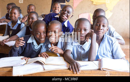 Uganda. Il 13 giugno 2017. Sorridente bambini ugandesi seduto alla scrivania in una classe in una scuola primaria. Foto Stock