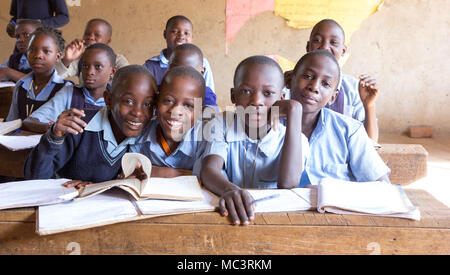 Uganda. Il 13 giugno 2017. Sorridente bambini ugandesi seduto alla scrivania in una classe in una scuola primaria. Foto Stock