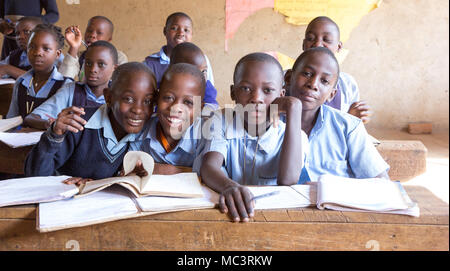 Uganda. Il 13 giugno 2017. Sorridente bambini ugandesi seduto alla scrivania in una classe in una scuola primaria. Foto Stock