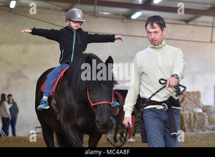 Un bambino a cavallo durante l'equino-terapia assistita (Mangiare) in Stritez, nella Repubblica ceca il 11 aprile 2018. Il DORADO civic society aiuta i bambini disabili per 25 anni. (CTK foto/Lubos Pavlicek) Foto Stock