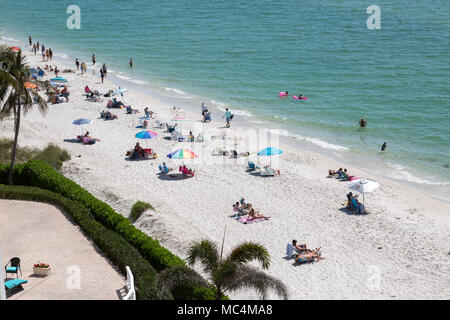 Vista da sopra della scena in spiaggia lungo la costa della Florida in Napoli. Le famiglie in vacanza su spring break. Colorato ombrelloni da spiaggia. Foto Stock