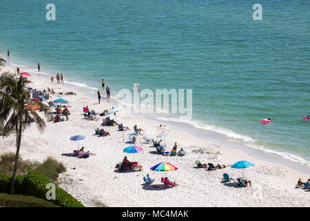 Vista da sopra della scena in spiaggia lungo la costa della Florida in Napoli. Le famiglie in vacanza su spring break. Colorato ombrelloni da spiaggia. Foto Stock