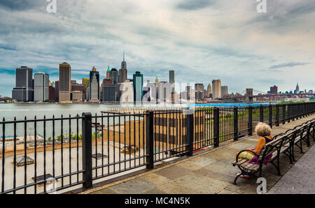 New York City, NY, Stati Uniti d'America - 16 Luglio 2014: Un misterioso lonely donna guarda inferiore dello skyline di Manhattan da Brooklyn Heights Promenade. Foto Stock