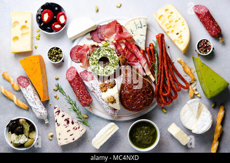 Italiano tradizionale di antipasto, tagliere con salame, freddo carne affumicata, prosciutto, prosciutto, formaggi, i capperi e le olive su sfondo grigio. Il formaggio e la carne antipasto. Vista superiore, copia dello spazio, laici piatta Foto Stock