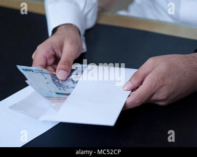 Imprenditore mani tenendo fuori i soldi al di fuori di un envelpoe Foto Stock