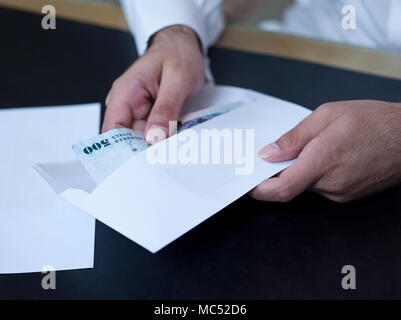 Imprenditore mani tenendo fuori i soldi al di fuori di un envelpoe Foto Stock