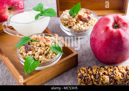 Cibi sani per la prima colazione. Cereali di avena con noci e uvetta, mele e yogurt su una tovaglia grigio closeup Foto Stock