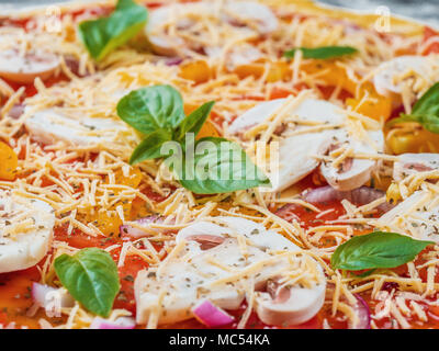 La pizza italiana con mozzarella e pomodoro guarnite con foglie di basilico fresco su una spessa crosta. Gli ingredienti alimentari e spezie per la cottura dei funghi, formaggi, Foto Stock