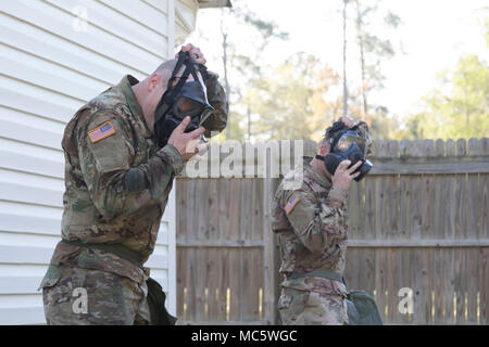 Due concorrenti don M50 Campo maschere protettive a Fort Stewart, Ga., 28 marzo 2018, prima di entrare in una camera del gas. Esecuzione di combattere le procedure salvavita in una sostanza chimica, biologica, radiologica, nucleare e ambiente esplosivo era uno dei vari eventi durante il sanitario regionale - Comando dell'Atlantic guerriero migliore concorrenza. Foto Stock