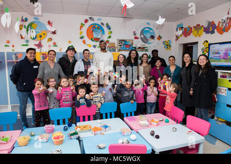 DEVESELU, Romania (28 marzo 2018) i marinai e i civili dalla base navale di meccanismo di sostegno Deveselu scattare una foto di gruppo con gli amministratori delle scuole e bambini dalla scuola Deveselu, una locale scuola rumena, durante un uovo di Pasqua le relazioni tra comunità (COMREL) progetto. NSF Deveselu AAMDS e Romania sono co-localizzato con il rumeno 99th Base Militare e gioca un ruolo chiave nel missile balistico di difesa in Europa orientale. Foto Stock