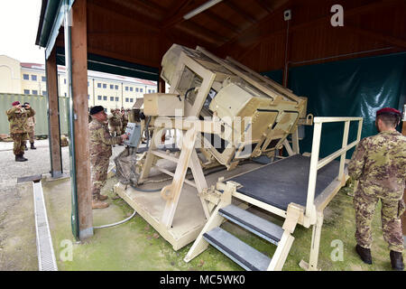 Sgt. Il Mag. Gaetano Massimo Giordano esercito italiano, assiste l'Esercito Italiano paracadutisti assegnato al reggimento "Savoia Cavalleria" Folgore Brigata Grosseto, durante il training con elevata mobilità multiuso di veicolo su ruote (HMMWV) assistenza egress trainer (calore), a Caserma Ederle Vicenza, Italia, 29 marzo 2018. Il simulatore consente ai soldati di pratica uscire dai veicoli, di competenze e di impegnarsi in scenari realistici. I paracadutisti italiani utilizzare U.S. RTSD esercito sud attrezzatura per migliorare le relazioni bilaterali e per espandere i livelli di cooperazione e la capacità del personale coinvolto in joint operatio Foto Stock