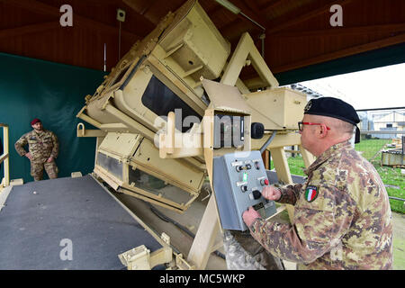 Sgt. Il Mag. Gaetano Massimo Giordano esercito italiano, assiste l'Esercito Italiano paracadutisti assegnato al reggimento "Savoia Cavalleria" Folgore Brigata Grosseto, durante il training con elevata mobilità multiuso di veicolo su ruote (HMMWV) assistenza egress trainer (calore), a Caserma Ederle Vicenza, Italia, 29 marzo 2018. Il simulatore consente ai soldati di pratica uscire dai veicoli, di competenze e di impegnarsi in scenari realistici. I paracadutisti italiani utilizzare U.S. RTSD esercito sud attrezzatura per migliorare le relazioni bilaterali e per espandere i livelli di cooperazione e la capacità del personale coinvolto in joint operatio Foto Stock