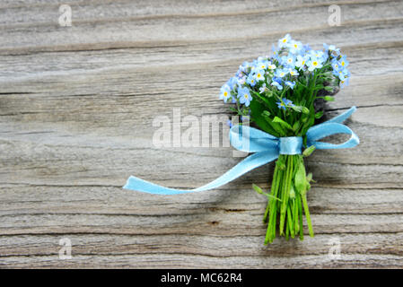 Piccolo bouquet di dimenticare blu-me-non fiori, legata con un nastro di colore blu, sullo sfondo della vecchia tavola in legno, con copy-spazio Foto Stock