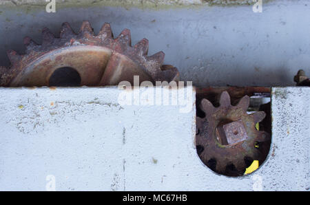 Vecchio arrugginito ruote dentate. Sullo sfondo il muro. Foto Stock