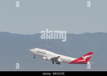Qantas Airways Boeing 747-400 Jet Climbing di distanza dall'Aeroporto Internazionale di Los Angeles LAX. Il Santa Monica montagne sullo sfondo. Foto Stock